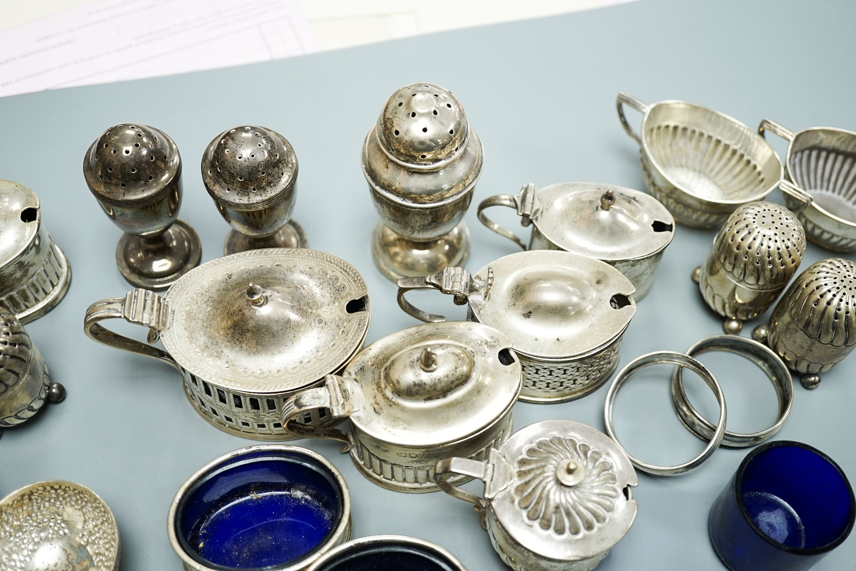 A mixed group of assorted mainly early 20th century silver condiments, including mustard pots, salts and pepperettes, two napkin rings and four plated salts, some lacking liners.